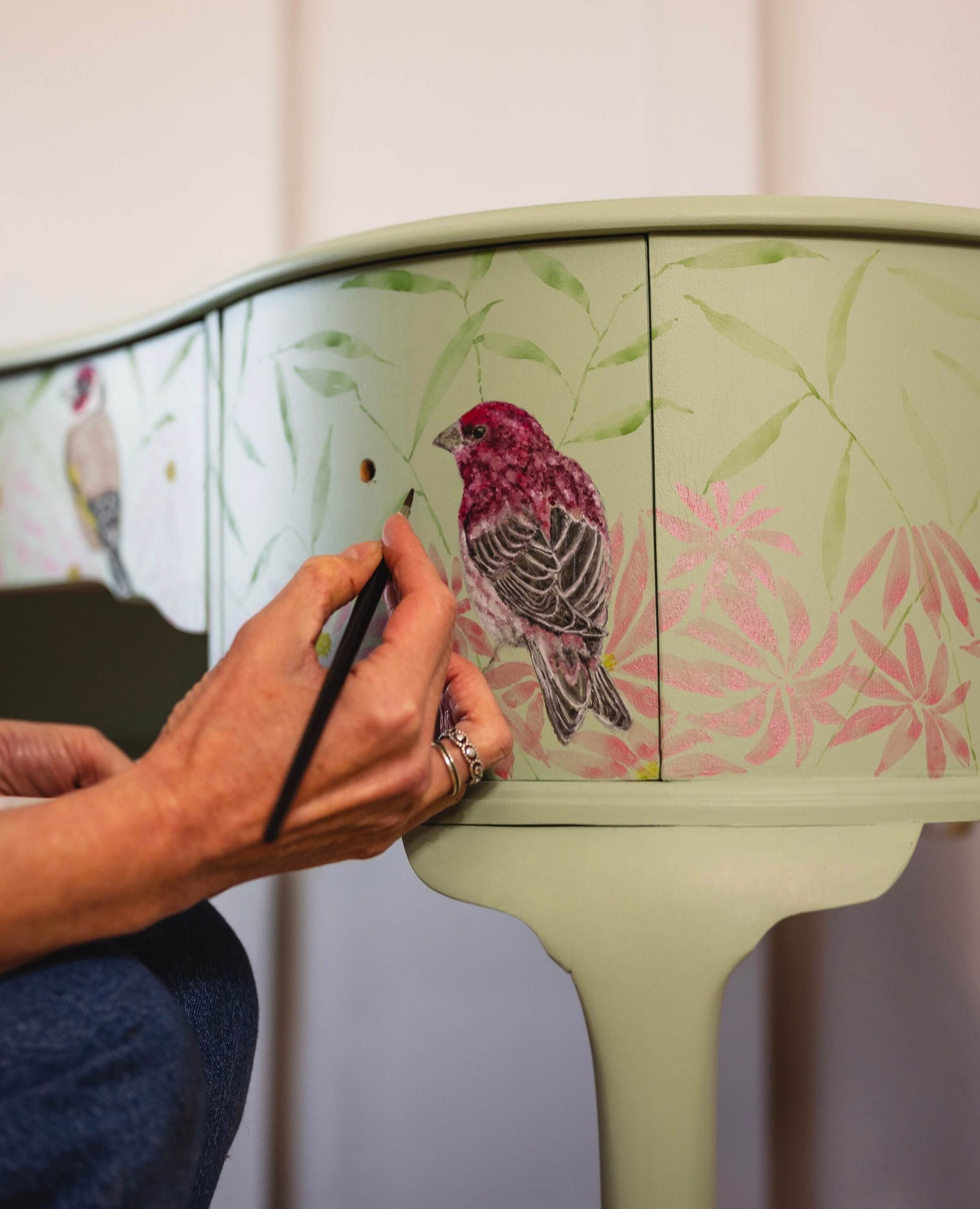 Artist painting watercolour bird onto vintage dressing table